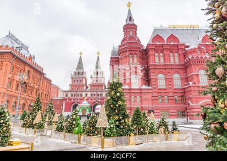 Moskau, Russland - 20. Dezember: Weihnachtlich geschmückter Manezhnaja-Platz an einem verschneiten Tag. Viele weihnachtsbäume auf dem Roten Platz und dem Staatlichen Historischen Museum Stockfoto