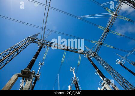 Elektrische Unterstation. Stromnetze, Masten, Drähte und Isolatoren (Isolatoren) am blauen Himmel. Weitwinkelobjektiv Stockfoto