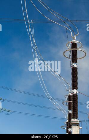 Krafthaus. Isolatoren (Isolatoren) und Drähte (Kabel) von Transformatorunterstationen am blauen Himmel. Hochspannungsausrüstung. Nahaufnahme. Stockfoto