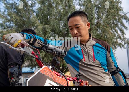 Urumqi. September 2020. Das am 10. September 2020 aufgenommene Foto zeigt den Motorradfahrer Gao Dongxu, der sein Fahrrad überprüft, bevor er in Urumqi, der nordwestlichen chinesischen Autonomen Region Xinjiang Uygur, unterwegs ist. Gao Dongxu, 39 Jahre alt, und seine Freunde sind Langlaufbegeisterte, die gerne neue Reitwege in den Bergen erkunden. Quelle: Hu Huhu/Xinhua/Alamy Live News Stockfoto