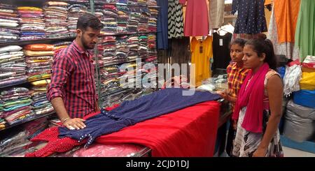 DISTRIKT KATNI, INDIEN - 18. SEPTEMBER 2019: Ein indischer Verkäufer zeigte während des indischen Festmarktangebotes den Mädchenkunden Tuch im Bekleidungsgeschäft Stockfoto