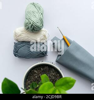 Drei Pastell farbige Kugeln aus Garn mit Häkelhaken und Baumwollstoff, flach gelegt Stockfoto