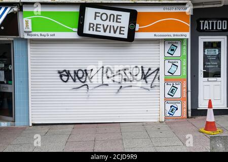 Hässliche Graffiti-Tags wurden auf die Fensterläden eines geschlossenen Ladens in Newquay Town in Cornwall gesprüht. Stockfoto