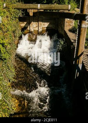 Ein Mühlbach mit einer alten Schleuse. Ihr könnt sehen, wie das Wasser durch sie fließt. Stockfoto