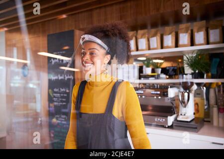 Weibliche Kleinunternehmerin Des Coffee Shops Mit Gesichtsschild Hinter Dem Zähler Während Der Gesundheitsinpandemie Stockfoto