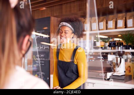 Lachende Frau, Die Im Coffee Shop Mit Gesichtsschild Arbeitet Kunde Während Einer Gesundheitsinpandemie Stockfoto