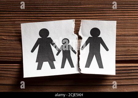 Beziehungen Brechen. Scheidung in der Familie. Der Mann verließ die Familie mit Kindern. Papier ist in zwei Hälften gerissen mit Symbol von Mann und Frau mit Kind. Stockfoto