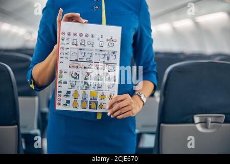 Professioneller Flugbegleiter, der Flugsicherheitsinformationen in einem Flugzeug vorführt Stockfoto