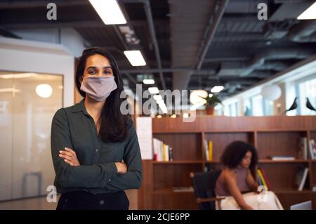 Porträt Der Geschäftsfrau Trägt Gesichtsmaske In Modernen Offenen Plan Büro Während Der Covid-19 Pandemie Stockfoto
