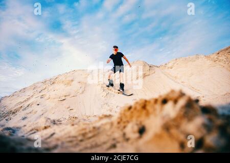 Extremer Absand auf Snowboard in der Wüste. Männlicher Snowboarder auf Dünen Stockfoto