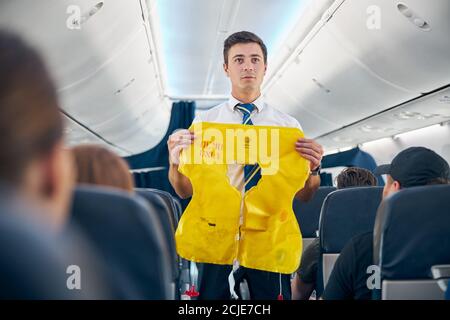 Steward demonstriert Flugregeln für die Sicherheit an Bord Stockfoto