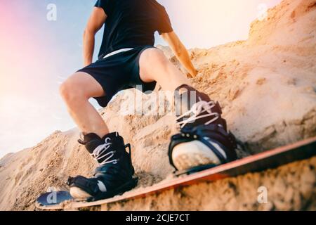 Extremer Absand auf Snowboard in der Wüste. Männlicher Snowboarder auf Dünen Stockfoto