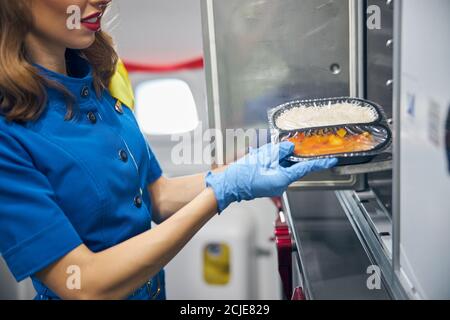 Stewardess serviert Essen für die Passagiere in der Küche von Verkehrsflugzeug Stockfoto