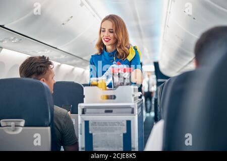 Flugbegleiter, der den Passagieren an Bord Speisen und Getränke serviert Stockfoto