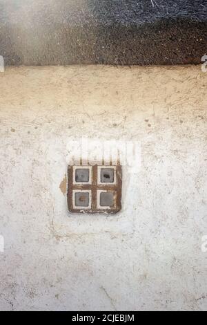 Alte Wand mit einem kleinen Fenster und Stroh Stockfoto
