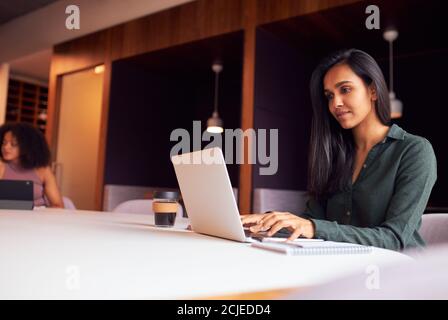 Geschäftsfrau, Die Am Laptop Bei Einem Sozial Distanzierten Meeting Im Büro Arbeitet Während Der Gesundheitsinpandemie Stockfoto