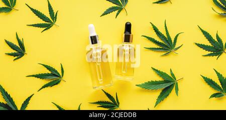 Hanföl-Serum in Glasflaschen mit Cannabisblättern. Cannabisblatt-Muster mit kosmetischem Produkt CBD-Öl auf gelbem Hintergrund langes Webbanner Stockfoto