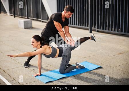 Sportliche männliche Hilfe junge Frau während des Trainings im Freien Stockfoto