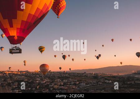 Kappadokien / Türkei - 14. September 2020: Fliegende Heißluftballons und Felslandschaft bei Sonnenaufgang in Goreme, Kappadokien, Türkei Stockfoto