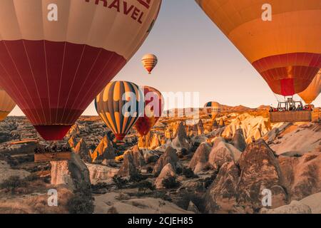 Kappadokien / Türkei - 14. September 2020: Fliegende Heißluftballons und Felslandschaft bei Sonnenaufgang in Goreme, Kappadokien, Türkei Stockfoto