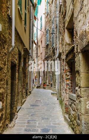 Toller Blick auf alte Häuser mit alten Fassaden auf einer typischen schmalen Straße im historischen Dorf Corniglia an der Küste von Cinque Terre, Ligurien,... Stockfoto