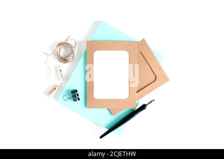 Stilvolles minimalistisches Design mit Rahmen aus Kraftpapier, Holzkachelnadeln, Garn, Kalligraphiestift, Clips, Minznotizblock auf weißem Hintergrund Stockfoto