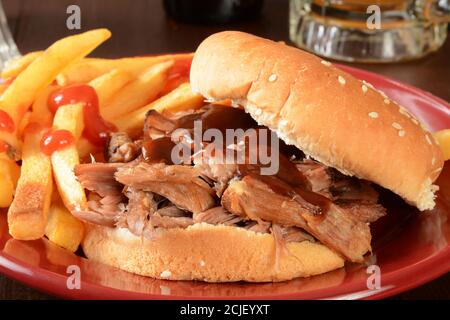 Ein Pulled-Pork-Sandwich mit Grillsauce, Pommes und Bier Stockfoto