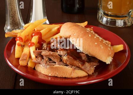 Ein Pulled-Pork-Sandwich mit Grillsauce und einem Becher Bier Stockfoto