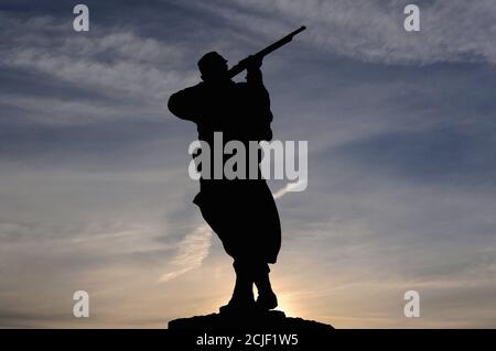 Bronzestatue eines französischen Infanteristen oder Poilu als Silhouette vor der aufgehenden Sonne. Denkmal in Monpazier in der Dordogne, Nouvelle-Aquitaine, Frankreich, für diejenigen, die im französisch-preußischen Krieg von 1870-71 gefallen sind. Stockfoto