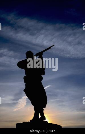 Bronzestatue eines französischen Schützen oder Poilu, Silhouette vor der aufgehenden Sonne. Denkmal in Monpazier in der Dordogne, Nouvelle-Aquitaine, Frankreich, für diejenigen, die im französisch-preußischen Krieg von 1870-71 gefallen sind. Stockfoto