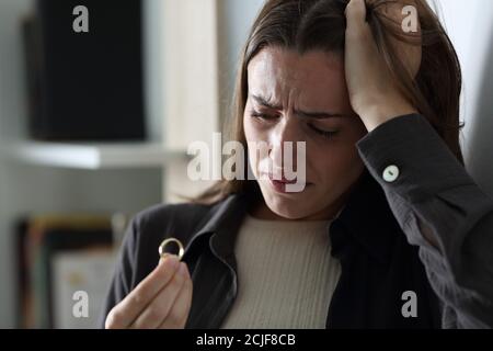 Traurige Frau beschwerte sich, als sie nachts den Ehering ansah Zu Hause Stockfoto