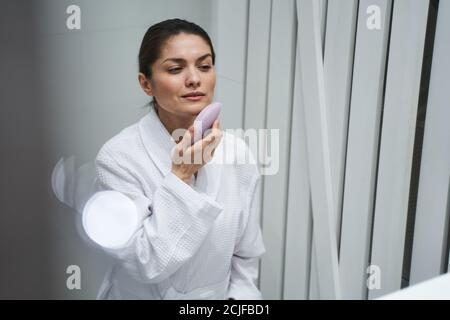 Fokussierte Dame, die ein Schönheitsverfahren zu Hause durchführt Stockfoto