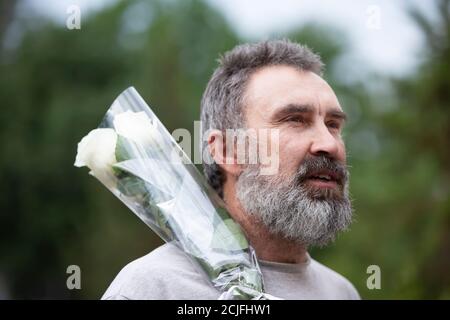 Porträt eines bärtigen Mannes mittleren Alters mit einem Blumenstrauß. Stockfoto