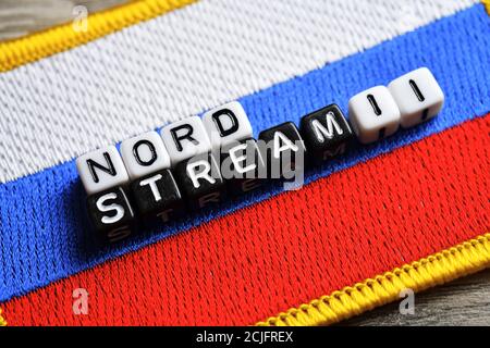 Buchstabenwürfel, die die Worte Nord Stream 2 auf der Flagge von Russland, Nord Stream 2 Gasleitung bilden Stockfoto