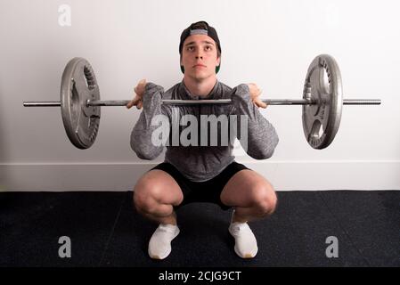 Junge fit männlich tut Kniebeugen mit einer Langhantel an der Fitnessraum Stockfoto