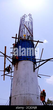 DISTRIKT KATNI, INDIEN - 16. JULI 2019: Indischer Straßenbauarbeiter klettert auf Zementmast für Überbrückung Schaffung am Himmel Hintergrund. Stockfoto