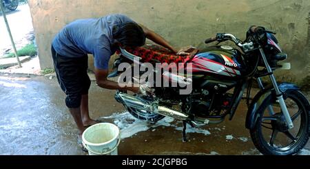 BEZIRK KATNI, INDIEN - 16. JULI 2019: Ein indischer Automobil-Service-Center Arbeiter Reinigung Motorrad in der Werkstatt. Stockfoto