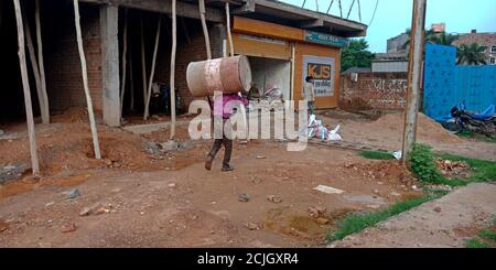 DISTRIKT KATNI, INDIEN - 04. AUGUST 2019: Ein indisches Dorf Arbeit Transport Eisentrommel auf Kopf auf Hausbaustelle. Stockfoto