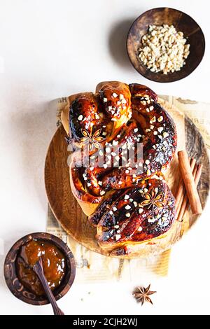 Babka oder Brioche Brot mit Aprikosenmarmelade und Nüssen. Hausgemachtes Gebäck zum Frühstück. Konkreter Hintergrund. Stockfoto