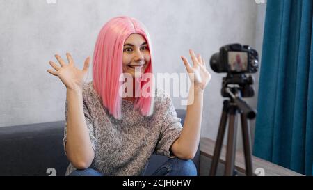 Happy girl blogger in rosa Perücken vor der Kamera auf einem Stativ. Sie nimmt einen Videoblog auf und kommuniziert mit Abonnenten in sozialen Netzwerken. Stockfoto