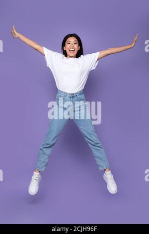 Fröhliche Aisan Frau Springen Spreadeagle Posiert Über Lila Hintergrund Stockfoto