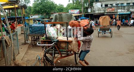 DISTRIKT KATNI, INDIEN - 12. AUGUST 2019: Ein indischer Rikscha-Fahrer lädt Gemüsesäcke auf der Straße durch Selbstversuche. Stockfoto