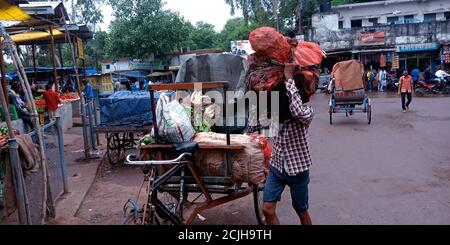 DISTRIKT KATNI, INDIEN - 12. AUGUST 2019: Ein indischer Rikscha-Fahrer entlädt Gemüsesäcke auf der Straße durch Selbstversuche. Stockfoto