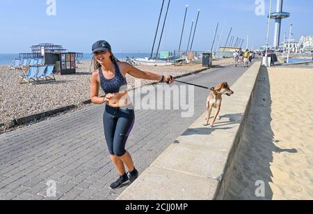Brighton UK 15. September 2020 - Diese junge Dame nimmt ihren Hund für einen Lauf an der Küste von Brighton, wie sie das Beste aus einem anderen heißen Tag am Meer machen, da die Temperaturen wieder erwartet werden, um 30 Grad in einigen Teilen des Südostens zu erreichen : Kredit Simon Dack / Alamy Live Nachrichten Stockfoto