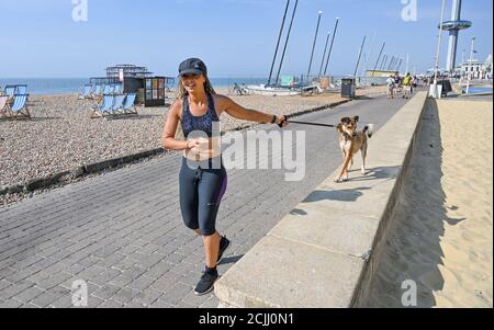 Brighton UK 15. September 2020 - Diese junge Dame nimmt ihren Hund für einen Lauf an der Küste von Brighton, wie sie das Beste aus einem anderen heißen Tag am Meer machen, da die Temperaturen wieder erwartet werden, um 30 Grad in einigen Teilen des Südostens zu erreichen : Kredit Simon Dack / Alamy Live Nachrichten Stockfoto