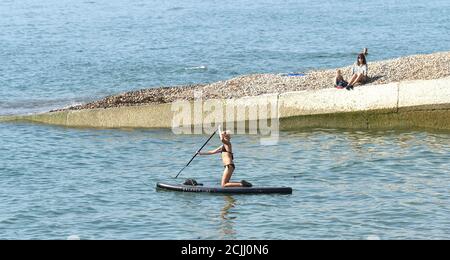 Brighton UK 15. September 2020 - EIN Paddelboarder vor Brighton Beach als Sonnenanbeter machen das Beste aus einem weiteren heißen Tag am Meer, da die Temperaturen in einigen Teilen des Südostens wieder 30 Grad erreichen werden : Credit Simon Dack / Alamy Live News Stockfoto