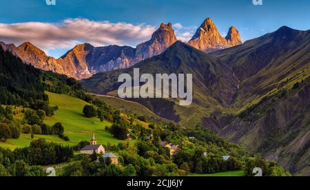 kirche in einem Dorf in den französischen alpen mit Bergen 3000 Meter hoch. Grüne Wiesen im Frühling Stockfoto