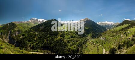 kirche in einem Dorf in den französischen alpen mit Bergen 3000 Meter hoch. Grüne Wiesen im Frühling. Drohnenschwenken Stockfoto