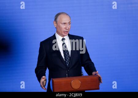 Präsident der Russischen Föderation Wladimir Putin steht hinter der Podium und spricht etwas vor dem Hintergrund eines blauen Wand Stockfoto