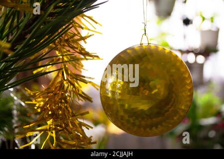Nahaufnahme einer gelben Kugel, die an einem geschmückten Weihnachtsbaum hängt. Retro-Filtereffekt. Stockfoto